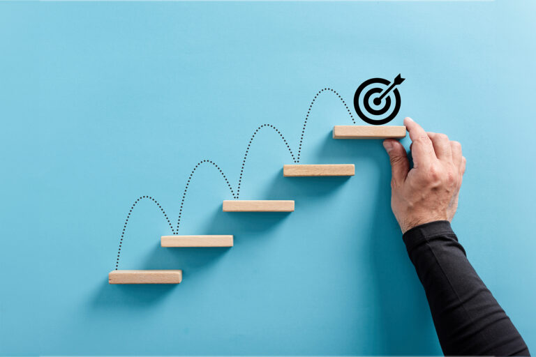 Male hand arranges a wooden block staircase with target icon. Achieving goals and objectives or goal setting
